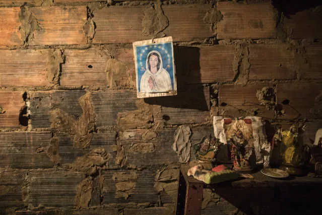 An image of the Virgin Mary hangs from a brick wall next to the room where the corpse of Teresa Jimenez is prepared following her death from natural causes at the age of 91 in Maracaibo, Venezuela, November 17, 2019. The cost of transporting a body, buying a casket and burial plot for a funeral can run into the hundreds of dollars, or more, while most earn the minimum wage of roughly $3 a month as hyperinflation devours pay. (Photo by Rodrigo Abd/AP Photo)