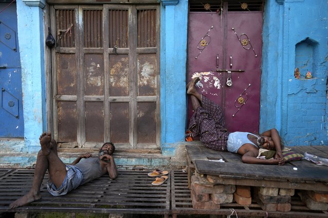 Indian laborers sleep in front of the closed shops in Prayagraj, India, Tuesday, May 10, 2022. A daily wage laborer if hired for a day earns about INR 500 (US$ 7). (Photo by Rajesh Kumar Singh/AP Photo)