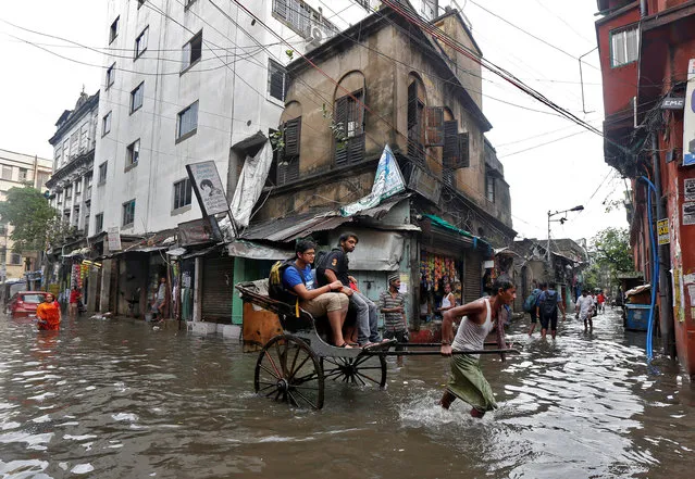 A rickshaw puller transports passengers through a water-logged street after heavy rain in Kolkata, India, July 7, 2017. (Photo by Rupak De Chowdhuri/Reuters)