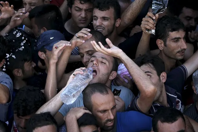 A Syrian refugee drinks water as he is packed in a crowded line during a registration procedure at the national stadium of the Greek island of Kos, August 12, 2015. (Photo by Alkis Konstantinidis/Reuters)
