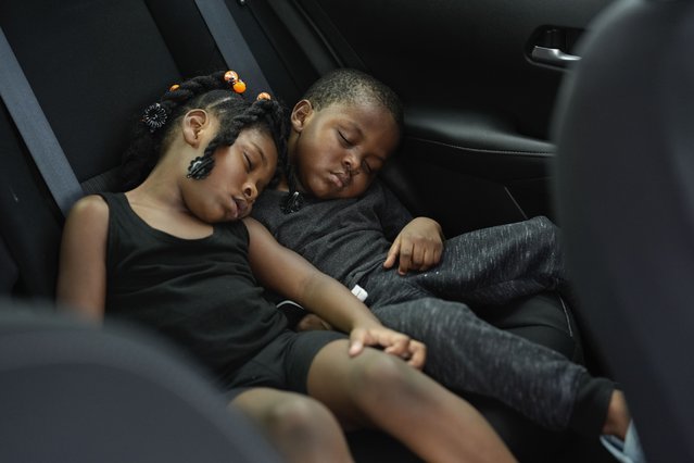 Siblings Saboria, 4, left, and Messiah Tyler, 3, nap in the backseat of a car after the roof was torn off the home where they lived with their mom, grandparents, an aunt and an uncle during the passage of Hurricane Milton, in Palmetto, Fla., Thursday, October 10, 2024. (Photo by Rebecca Blackwell/AP Photo)