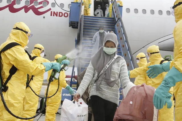 In this photo released by Indonesian Foreign Ministry, Indonesian people who arrived from Wuhan, China, are sprayed antiseptic at Hang Nadim Airport in Batam, Indonesia Sunday, February 2, 2020. Indonesians evacuated from Wuhan, the Chinese city at the center of a deadly virus outbreak, were transported to a quarantine zone on a remote island at the edge of the South China Sea, shortly after landed on Batam, an island near Singapore on Sunday morning. (Photo by Indonesian Foreign Ministry via AP Photo)