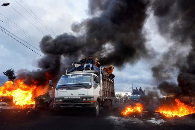 Indigenous demonstrators drive past burning road blockades while heading towards the capital Quito after a week of protests against the economic and social policies of President Guillermo Lasso, in Machachi, Ecuador on June 20, 2022. (Photo by Johanna Alarcon/Reuters)