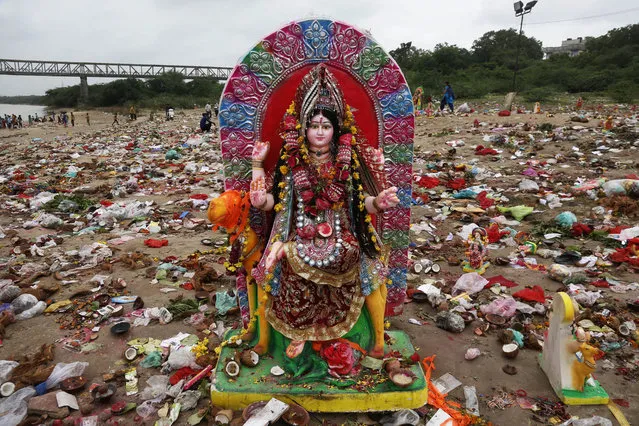 An idol of Hindu goddess Dashama stands among offerings and worship materials on the bank of river Sabarmati after the end of Dashama festival in Ahmadabad, India, Wednesday, August 2, 2017. The ten-days festival celebrated in the Shravan month of the Hindu calendar culminates with the immersion of the idols of this deity who is worshipped in this western Gujarat state. (Photo by Ajit Solanki/AP Photo)