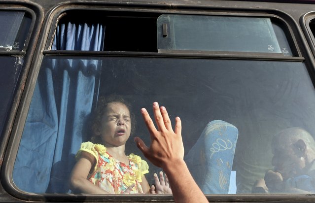 A Palestinian girl sitting in a bus reacts as she waits with her family to cross into Egypt at the Rafah border crossing between Egypt and the southern Gaza Strip August 17, 2015. Egypt opened the Rafah border crossing on Monday for four days to allow Palestinians to travel in and out of the Gaza Strip for the first time in around two months, officials said. (Photo by Ibraheem Abu Mustafa/Reuters)