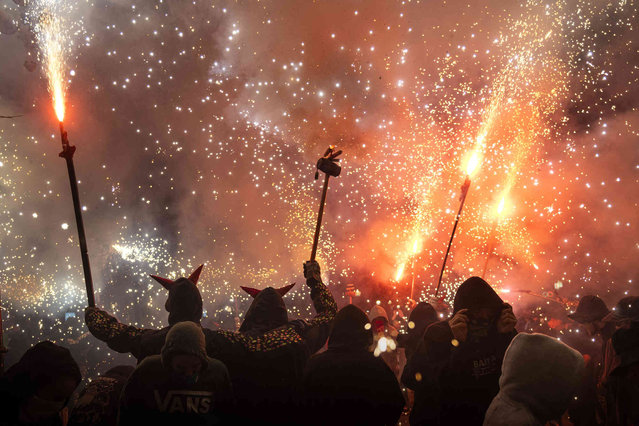 People dance as revelers hold fireworks as they take part in a “Correfoc”, or run with fire, party in Barcelona, Spain, Saturday September 14, 2024. (Photo by Emilio Morenatti/AP Photo)