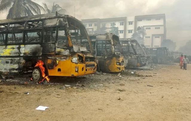 People walk past damaged school buses that were set on fire by a mob in the school campus after a female student's death in Kallakurichi district in the southern state of Tamil Nadu, India on July 17, 2022. (Photo by Reuters/Stringer)