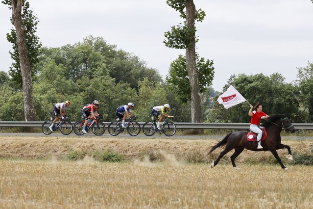 A woman rides a horse next to the breakaway group of (L-R) German rider Nils Politt of Bora Hansgrohe, US rider Quinn Simmons of Trek Segafredo, Slovenian rider Matej Mohoric of Bahrain Victorious, Danish rider Mikkel Honore of Quick-Step Alpha Vinyl Team and Dutch rider Taco Van Der Hoorn of Intermarche Wanty Gobert Materiaux during the 19th stage of the Tour de France 2022 over 188.3km from Castelnau-Magnoac to Cahors, France, 22 July 2022. (Photo by Yoan Valat//EPA/EFE/Rex Features/Shutterstock)
