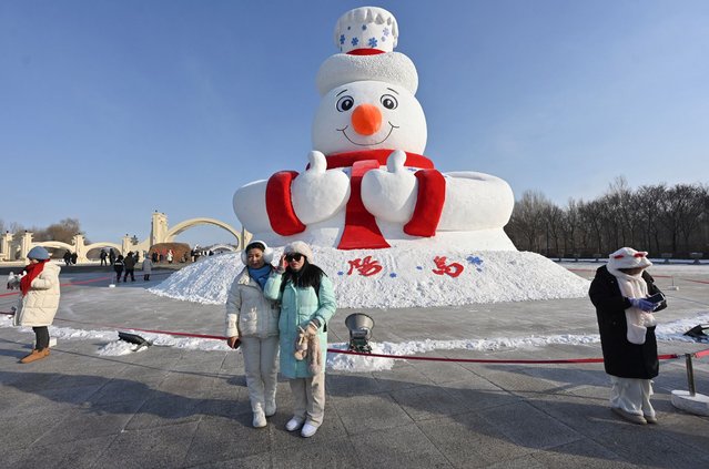Visitors pose for pictures with a snowman sculpture ahead of the annual Harbin Ice and Snow World festival in Harbin, China's northeast Heilongjiang province on December 17, 2024. (Photo by Adek Berry/AFP Photo)