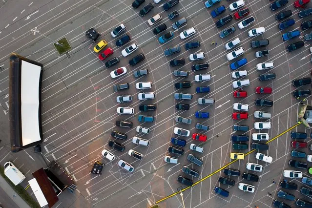 Visitors stand with their cars in the drive-in cinema in Chemnitz, Saxony on April 22, 2020. This is the first time since the beginning of the contact restrictions that there is a cinema in the city. Up to 230 vehicles can park on the square in front of the 200 square meter screen or the 50 square meter LED wall. Until 25 June, there will be a children's and family film every day at 5 pm and the evening programme at 8 pm. On Fridays and Saturdays there will be a midnight film from 23:00. (Photo by Jan Woitas/dpa-Zentralbild/dpa via Getty Images)
