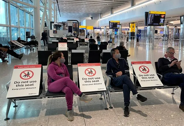 People sit amongst socially-distanced seating signs at Heathrow Airport, as the spread of the coronavirus disease (COVID-19) continues, in London, Britain, May 10, 2020. (Photo by Toby Melville/Reuters)