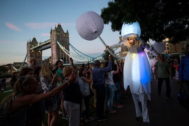 A performer on stilts wearing an inflatable lit costume ducks as she passes under a tree during The Night Time Lit Carnival around More London on the south bank of the River Thames on August 6, 2016 in London, England. The procession is part of the Night of Festivals, a series of events being held this weekend in celebration of the opening weekend of the Rio Olympics. (Photo by Jack Taylor/Getty Images)