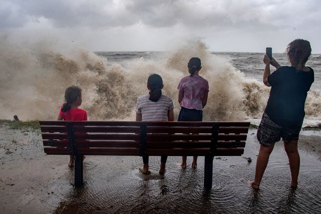 A family watch the storm roll in across the Coral Sea at Holloways Beach as Cyclone Jasper approaches landfall in Cairns in far north Queensland on December 13, 2023. A tropical cyclone was building strength as it rolled towards northeastern Australia on 13 December, with authorities warning “life-threatening” floods could swamp coastal regions for days. (Photo by Brian Cassey/AFP Photo)