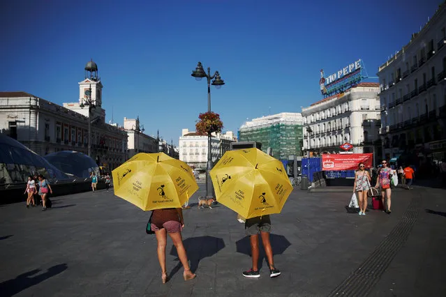 Tour guides wait for tourists at Puerta del Sol square in Madrid, Spain, August 1, 2016. (Photo by Susana Vera/Reuters)