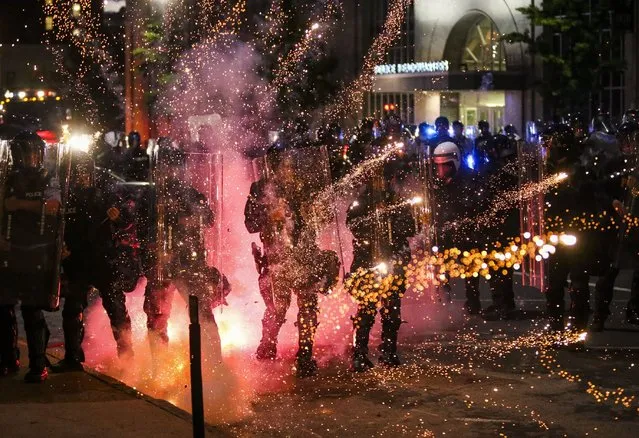 Fireworks go off in front of police, who with protesters in front of police headquarters in St. Louis on Monday, June 1, 2020. The small group of protesters was originally part of a much larger group demonstrating earlier in the afternoon against the death of George Floyd. (Photo by Colter Peterson/St. Louis Post-Dispatch via AP Photo)