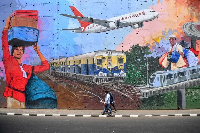 Pedestrians walk past a mural depicting various forms of transportation after the government eased a nationwide lockdown imposed as a preventive measure against the COVID-19 coronavirus, in Mumbai on May 21, 2020. Domestic air travel will resume in India on May 25 after a two-month shutdown imposed to stop the spread of coronavirus, the aviation minister said on May 20, in a further easing of national lockdown restrictions. (Photo by Indranil Mukherjee/AFP Photo)