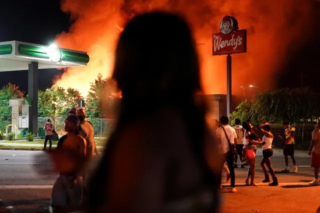 People watch as a Wendy’s burns following a rally against racial inequality and the police shooting death of Rayshard Brooks, in Atlanta, Georgia, June 13, 2020. Protesters shut down a major highway and burned down a Wendy's restaurant where a black man was shot dead by police as he tried to escape arrest, an incident likely to fuel more nationwide tensions over race and police tactics. (Photo by Elijah Nouvelage/Reuters)