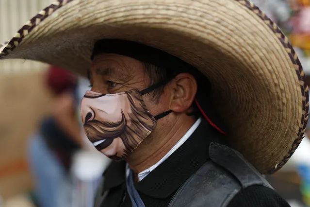 A man wearing a face mask walks amidst outdoor stalls at Mercado Sonora, which reopened ten days ago with measures to reduce congestion and limit the spread of the coronavirus, in Mexico City, Thursday, June 25, 2020. (Photo by Rebecca Blackwell/AP Photo)
