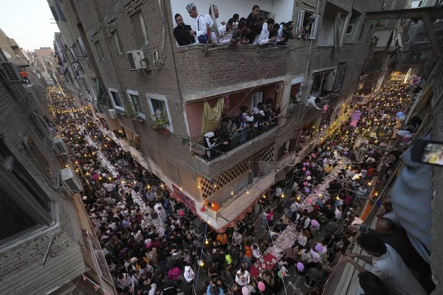 Residents of Ezbet Hamada in Cairo's El Matareya district peer from their balconies to celebrate a mass break-fast, “Iftar” during the holy fasting month of Ramadan in Cairo, Egypt, Saturday, March 15, 2025. (Photo by Amr Nabil/AP Photo)
