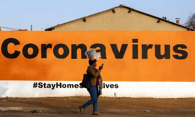 In this Friday June 19, 2020, a woman wearing a face mask passes a coronavirus billboard carrying a message in a bid to prevent the spread of the virus. South Africa's Health Minister Zwelini Mkhize said Sunday June 28, 2020 the country's current surge of COVID-19 cases is expected to dramatically increase in the coming weeks and press the country's hospitals to the limit. (Photo by Themba Hadebe/AP Photo/File)
