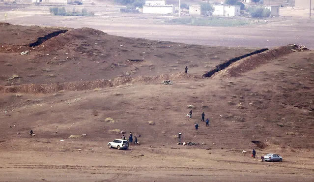 Kurdish fighters from the Syrian town of Kobani walks torwards trenches near the Mursitpinar border crossing on the Turkish-Syrian border in the southeastern town of Suruc in Sanliurfa province, October 17, 2014. (Photo by Kai Pfaffenbach/Reuters)