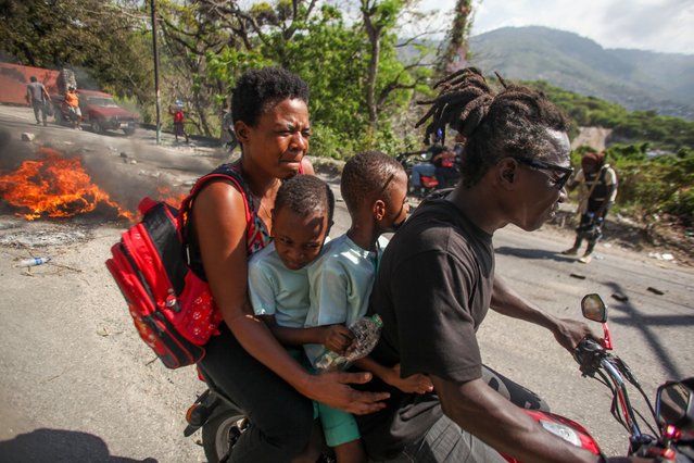 A family drives past protests against insecurity and gang violence in Port-Au-Prince, Haiti on March 27, 2025. Protesters are demand the departure of the Transitional Presidential Council but authorities have left downtown to escape the armed gang attacks. (Photo by Patrice Noel/ZUMA Press Wire/Rex Features/Shutterstock)