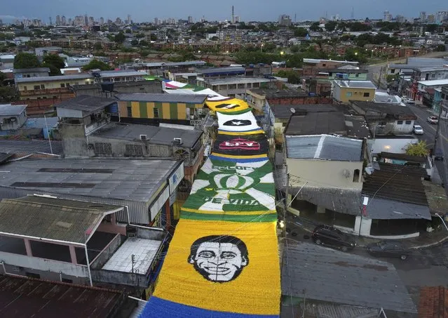 Seen from above, an image of soccer star Pele made from plastic ribbons decorates a street, amid other soccer related symbols, during the World Cup hosted by Qatar, in the Morro da Liberdade neighborhood of Manaus in Amazonas state, Brazil, early Monday, December 5, 2022. Pele has been in the hospital since Tuesday and officials say he is responding well to treatment for a respiratory infection. (Photo by Edmar Barros/AP Photo)