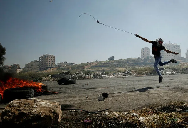 A Palestinian protester uses a sling to hurl stones towards Israeli troops during clashes at a protest in support of Palestinian prisoners on hunger strike in Israeli jails, near the Jewish settlement of Beit El, near the West Bank city of Ramallah, May 11, 2017. (Photo by Mohamad Torokman/Reuters)