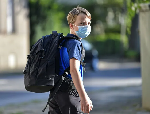 Pupil Moritz is on his way to the first day at his new school in Gelsenkirchen, Germany, Wednesday, August 12, 2020. Students in North Rhine-Westphalia will have to wear face masks at all times due to the coronavirus pandemic as they return to school this Wednesday. (Photo by Martin Meissner/AP Photo)