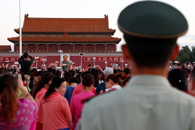 People take pictures during the flag raising ceremony on Tiananmen Square as the portrait of China's late Chairman Mao Zedong is seen in the background in Beijing, China, on the 40th anniversary of his death September 9, 2016. (Photo by Thomas Peter/Reuters)