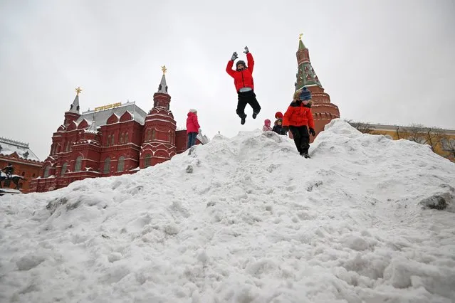 Children play with snow cleared from a square in Moscow on December 17, 2022. (Photo by Natalia Kolesnikova/AFP Photo)