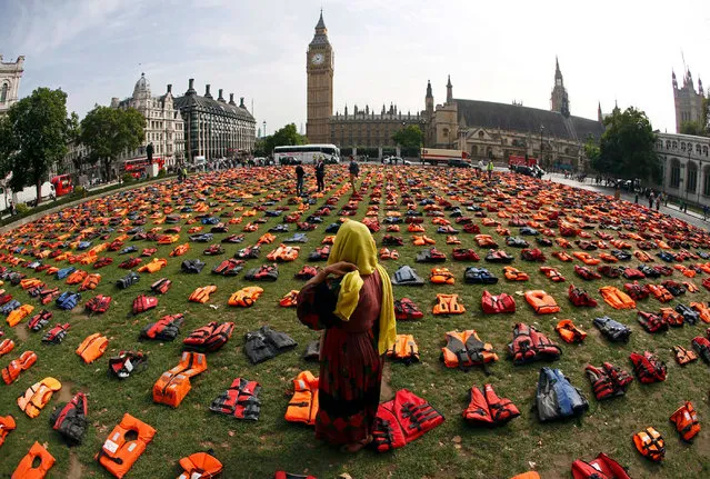 Rehab Sidiqi, a trustee of the charity Women for Refugee Women and originally from Afghanistan, stands in London’s Parliament Square Monday, September 19, 2016 among 2,500 lifejackets worn by refugees who crossed from Turkey to the Greek island of Chois. The display was organised by Snappin' Turtle Productions and supported by refugee charities to coincide with the first ever United Nations Summit for Refugees and Migrants taking place in New York later today. (Photo by Stefan Wermuth/Reuters)