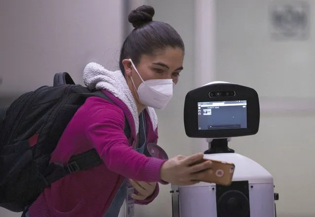 A healthcare worker poses for a photo with Laluchy Robotina, a robot designed to aid in the mental health of patients infected with the new coronavirus, in the COVID-19 ward at 20 de November National Medical Center in Mexico City, Friday, September 25, 2020. The 1.4-meter-tall robot that moves around on wheels visiting COVID-19 patients, is equipped with a camera and display screen which allows the patients to visit with relatives and to also communicate with healthcare workers, helping to reduce the risk of infection. (Photo by Marco Ugarte/AP Photo)