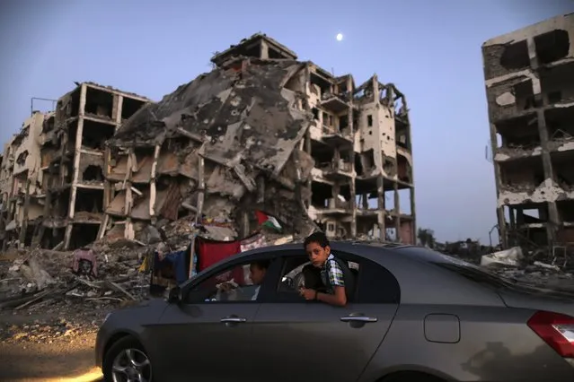 A Palestinian boy rides in a car driving past residential buildings in Beit Lahiya town, which witnesses said was heavily hit by Israeli shelling and air strikes during the Israeli offensive, in the northern Gaza Strip, in this August 7, 2014 file photo. (Photo by Mohammed Salem/Reuters)