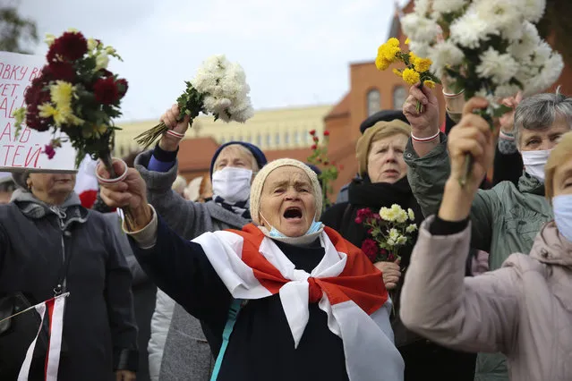People, most of them pensioners, wave bunches of flowers during an opposition rally to protest the official presidential election results in Minsk, Belarus, Monday, October 26, 2020. Factory workers, students and business owners in Belarus have started a general strike, calling for authoritarian President Alexander Lukashenko to resign after more than two months of mass protests triggered by a disputed election. (Photo by AP Photo/Stringer)