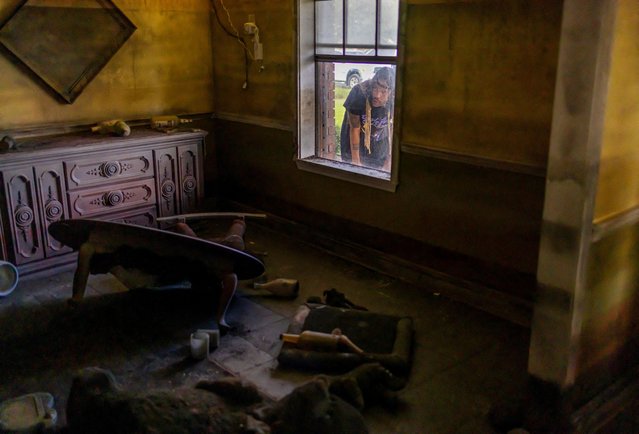 New Orleans native and Katrina evacuee Lonnie St. Junior II, who lives in Dallas now, looks through a window at the flooded House Museum, a one-of-a-kind life-sized diorama replicating what neighborhood homes looked like after Hurricane Katrina's floodwall failures, created in a gutted house next to the London Avenue Canal, as the 20th anniversary of Katrina draws near in New Orleans, Louisiana, on August 20, 2025. (Photo by Kathleen Flynn/Reuters)