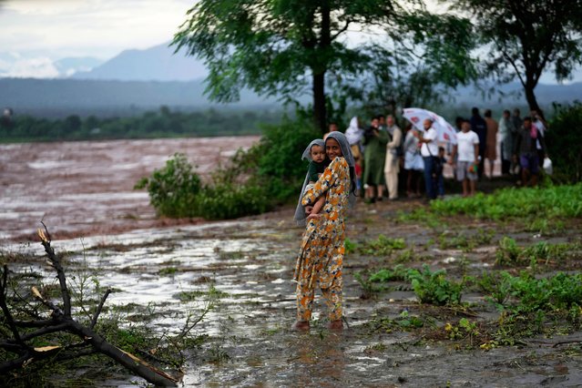 A girl carries a baby while waiting for their relatives during rescue operations, as residents evacuate their homes and move to safer areas after the River Chenab overflowed due to heavy rainfall, breaching the danger mark at Village Garkhal in Akhnoor, India, Wednesday, September 3, 2025. (Photo by Channi Anand/AP Photo)