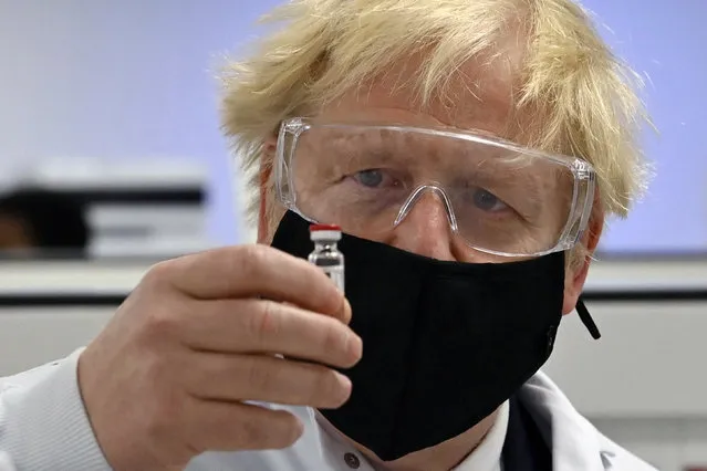 Britain's Prime Minister Boris Johnson holds a vial of the Oxford/AstraZeneca vaccine Covid-19 candidate vaccine, known as AZD1222, at Wockhardt's pharmaceutical manufacturing facility in Wrexham, Wales, Monday, November 30, 2020. (Photo by Paul Ellis/PA Wire via AP Photo)