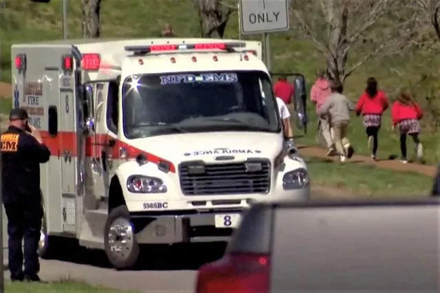 Children run past an ambulance near the Covenant School after a shooting in Nashville, Tennessee, U.S. March 27, 2023 in a still image from video. (Photo by WKRN/NewsNation via Reuters)