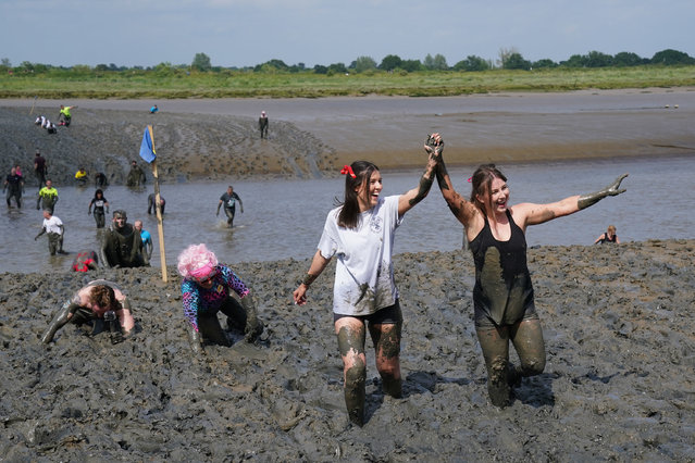 Competitors take part in the annual Maldon Mud Race, a charity event to race across the bed of the River Blackwater in Essex, UK on June 2, 2024. The race originated in 1973, with a dare being given by a local resident to the landlord of the Queens Head public house, which stands on the Hythe Quay in Maldon, challenging him to serve a meal on the saltings of the Rivers Blackwater dressed in a dinner jacket. The challenge was accepted and carried out, resulting next year in a bar being opened on the saltings. (Photo by Gareth Fuller/PA Images via Getty Images)