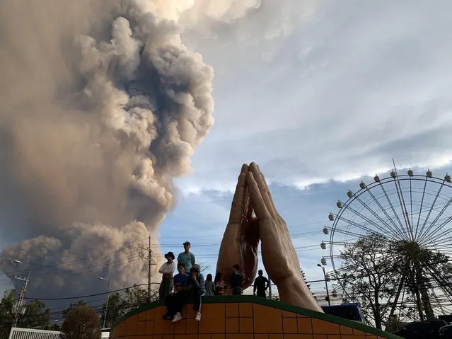 People watch as the Taal volcano spews ash and smoke during an eruption in Tagaytay, Cavite province south of Manila, Philippines on Sunday. January 12, 2020. A tiny volcano near the Philippine capital that draws many tourists for its picturesque setting in a lake belched steam, ash and rocks in a huge plume Sunday, prompting thousands of residents to flee and officials to temporarily suspend flights. (Photo by Bullit Marquez/AP Photo)