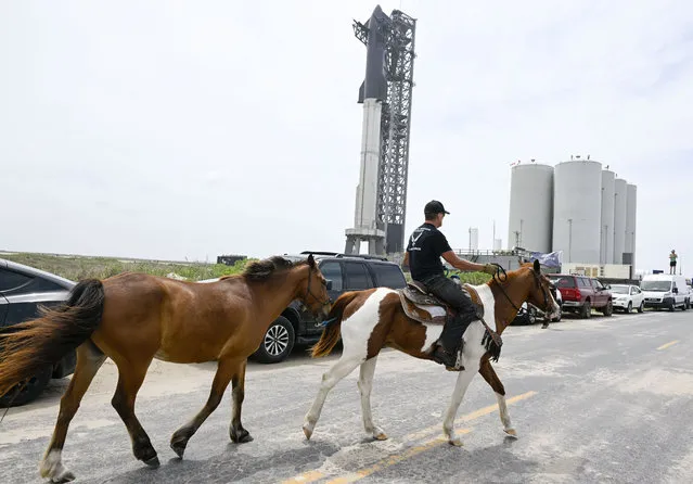 Local resident Gene Gore rides his horse Texas and pulls Disco as he checks out the SpaceX Starship spacecraft and Super Heavy rocket on the launch pad at Starbase on April 16, 2023. (Photo by Jonathan Newton/The Washington Post)