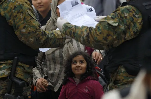 Macedonian police check the documents of migrants as they wait to cross the border from Greece into Macedonia, near Gevgelija, Macedonia November 21, 2015. (Photo by Ognen Teofilovski/Reuters)