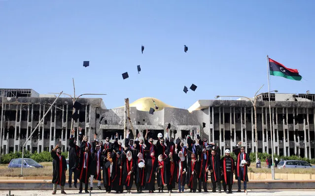 New graduates of Engineering and Law faculties at Benghazi University celebrate as they pose in front of damaged buildings at their university former headquarters, which was destroyed during clashes in 2014, between members of the Libyan National Army and Shura Council of Libyan Revolutionaries, an alliance of former anti-Gaddafi rebels who have joined forces with Islamist group Ansar al-Sharia, in Benghazi, Libya, October 27, 2016. (Photo by Esam Omran Al-Fetori/Reuters)