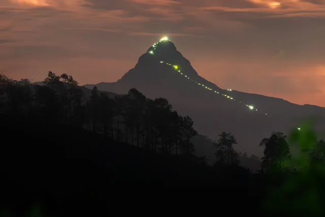 A bulb-light path and general view of the Adam's Peak mountain in Hatton, Sri Lanka, on April 22, 2023. Sri Pada, or Adam's Peak, is an ancient pilgrimage site that has long attracted thousands of pilgrims from all faiths. This conical mountain is 7,360 feet (2,250 meters) high, soaring clear above the surrounding mountain ranges. The mountain is located in the southern reaches of the Central Highlands in the Ratnapura District and Nuwara Eliya District of the Sabaragamuwa Province and Central Province, lying about 40 km northeast of the city of Ratnapura and 32 km southwest of the city of Hatton. The surrounding region is largely forested, with no mountains of comparable size nearby. The region along the mountain is a wildlife reserve, housing many species ranging from elephants to leopards and including many endemic species. The region of Peak Wilderness Sanctuary that encompasses the Sri Pada together with Horton Plains National Park and Knuckles Range, all in the Central Highlands of Sri Lanka, was recognized as a World Heritage Site in 2011. (Photo by Thilina Kaluthotage/NurPhoto via Getty Images)