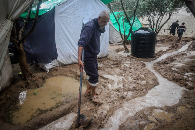 A Palestinian man attempts to drain water from a makeshift shelter in Gaza City on November 25, 2025. (Photo by Habboub Ramez/Abaca Predd/Shutterstock)