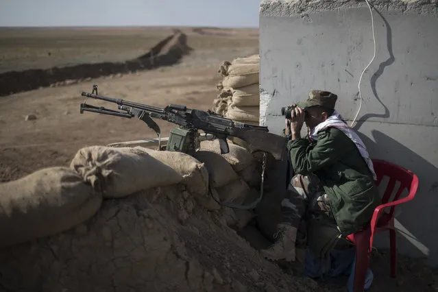 A Kurdish Peshmerga soldier observes Islamic State-held territory through binoculars at a frontline position near Khorsabad, north of Mosul, Iraq, Wednesday, November 2, 2016. (Photo by Felipe Dana/AP Photo)