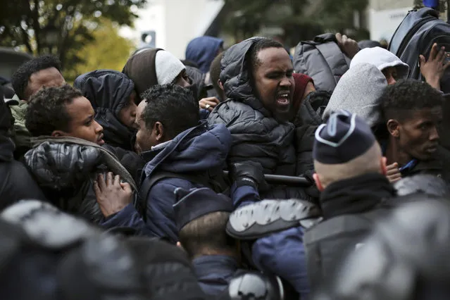 Migrants are pushed back by police officers as they wait to board buses to temporary shelters in Paris, Friday, November 4, 2016. Police and city officials are clearing out hundreds of migrants camped out on sidewalks in northern Paris in a camp that recently grew into a new challenge for the French government. (Photo by Thibault Camus/AP Photo)