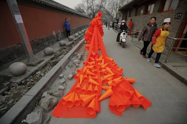 Chinese artist Kong Ning walks through a historical part of Beijing in her costume made of hundreds of orange plastic blowing horns during her art performance raising awareness of the hazardous smog on a very polluted day December 7, 2015. (Photo by Damir Sagolj/Reuters)
