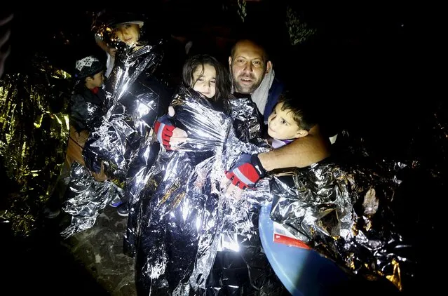 A Syrian refugee tries to keep his children warm after being rescued by Greek fishermen on the Greek island of Lesbos October 19, 2015. (Photo by Yannis Behrakis/Reuters)
